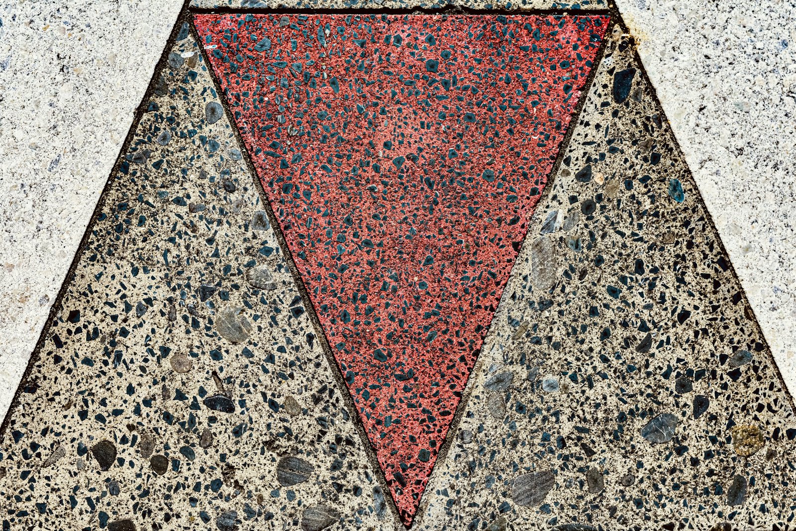 Red triangular inlay set into speckled, polished aggregate concrete