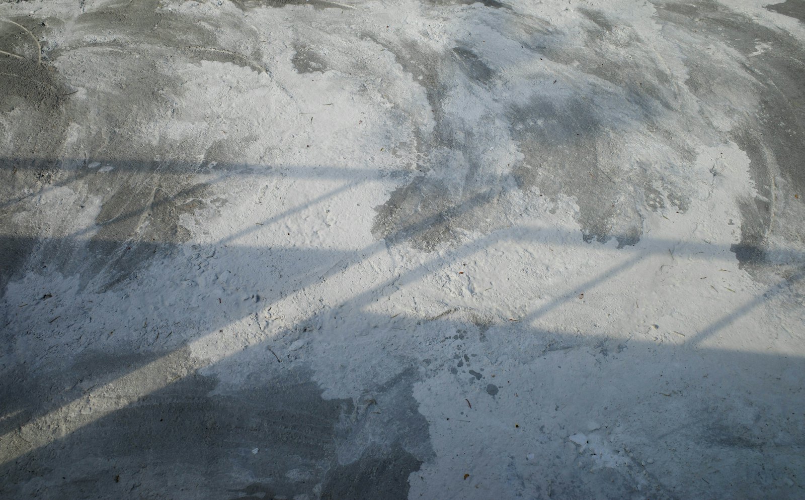 Mottled grey and white concrete floor with soft window light falling across it