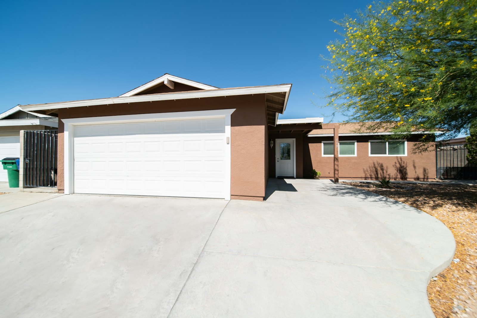 Freshly poured concrete driveway leading to a white two-car garage on a ranch-style home