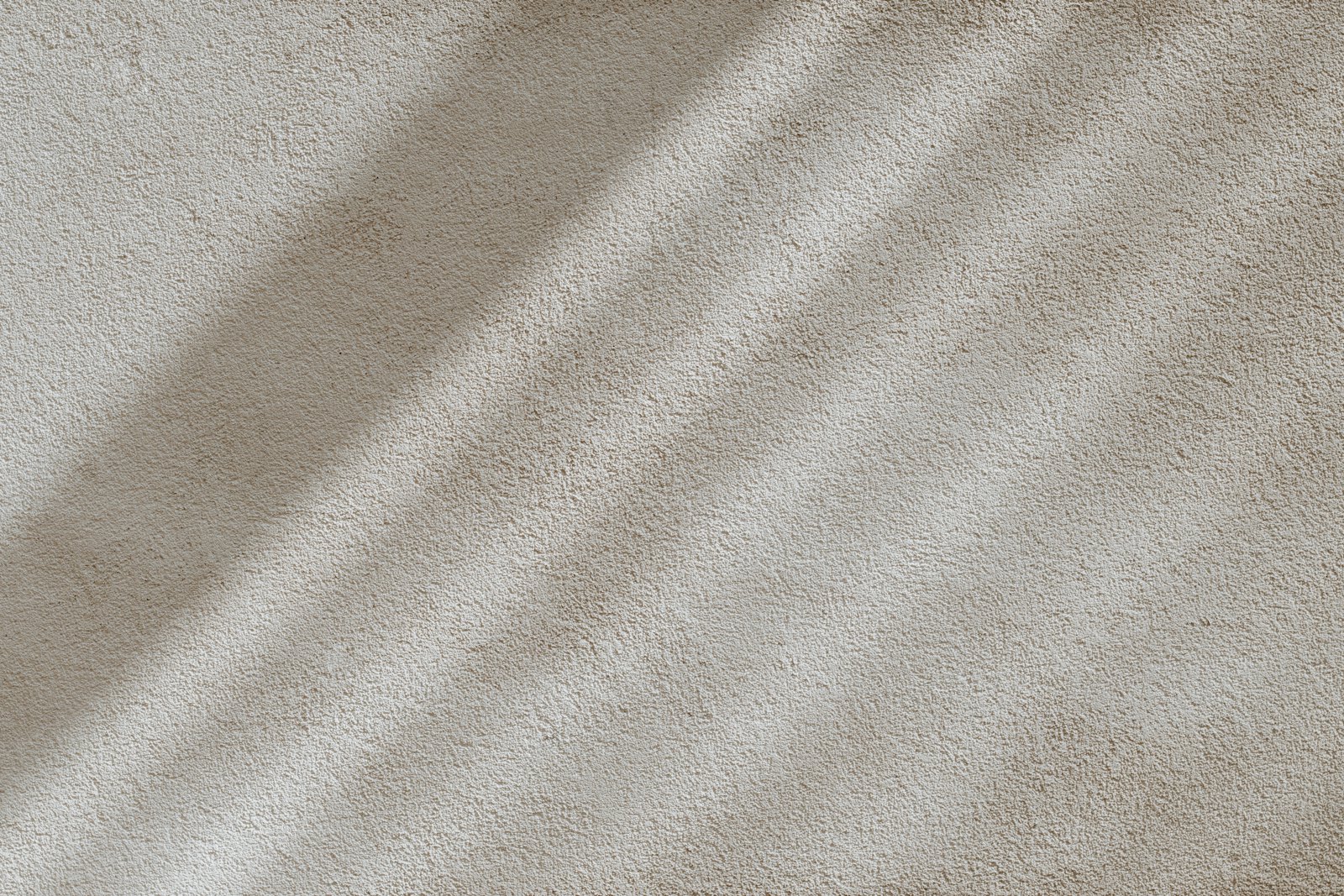 Beige textured surface crossed by soft diagonal light and shadow