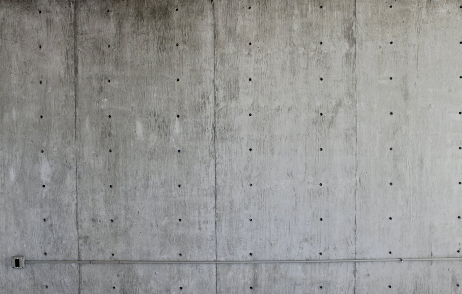 Board-formed concrete wall panels with a grid of form-tie holes